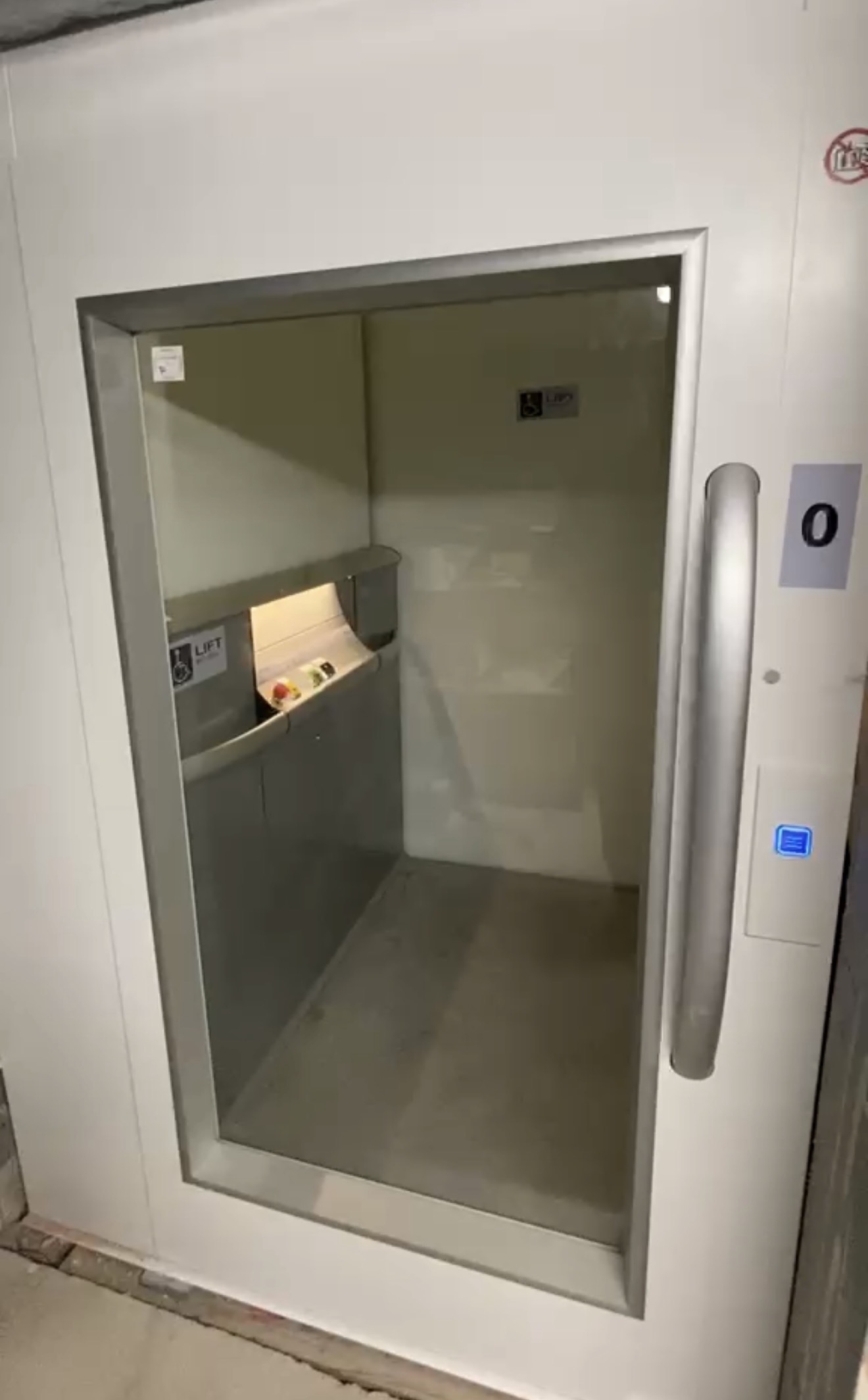 Small lift with a glazed door and a visible serving shelf