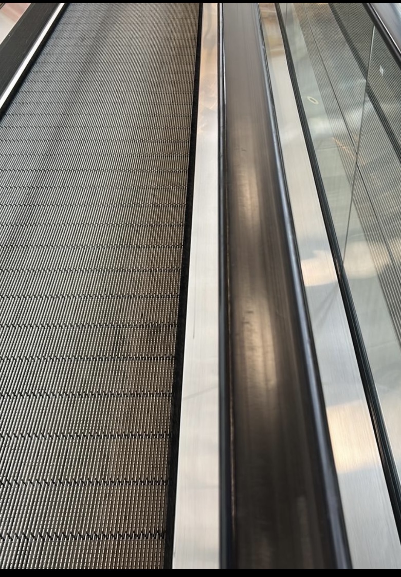 Travelator belt between glass sides and handrails