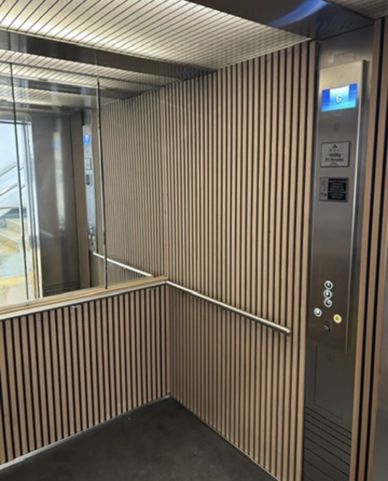 Lift interior with timber slat walls, mirror and a metal operating panel